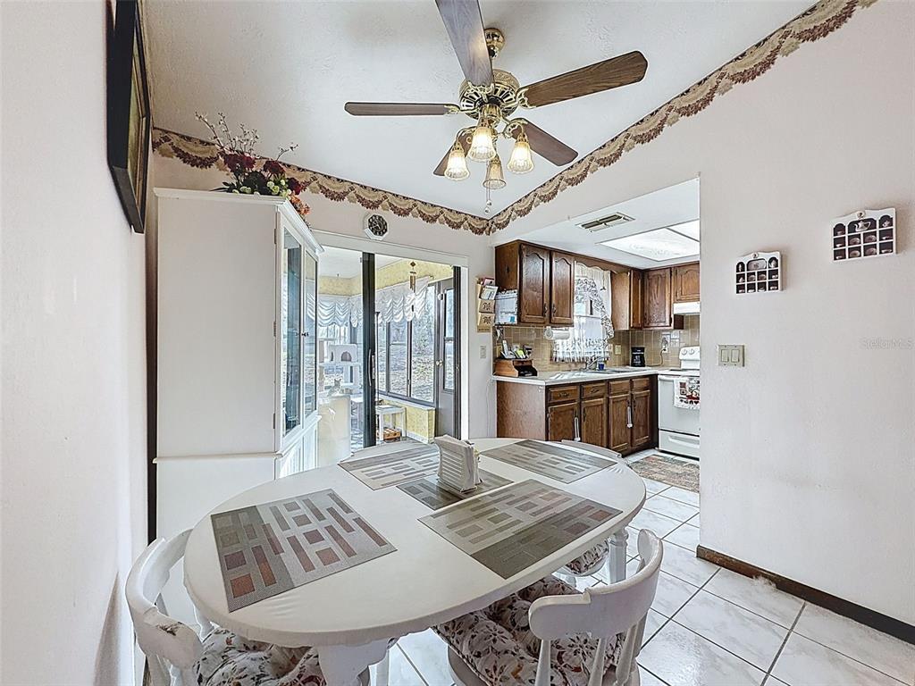 12229 Cedro Street Spring Hill, FL 34609 - Photo 16 of 50 a open kitchen with stainless steel appliances granite countertop a stove a refrigerator a dining table and chairs with wooden floor