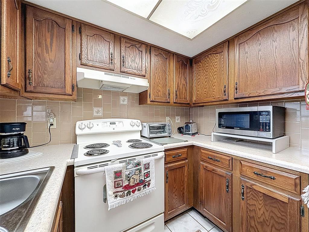 12229 Cedro Street Spring Hill, FL 34609 - Photo 19 of 50 a kitchen with stainless steel appliances granite countertop a stove a sink and a microwave