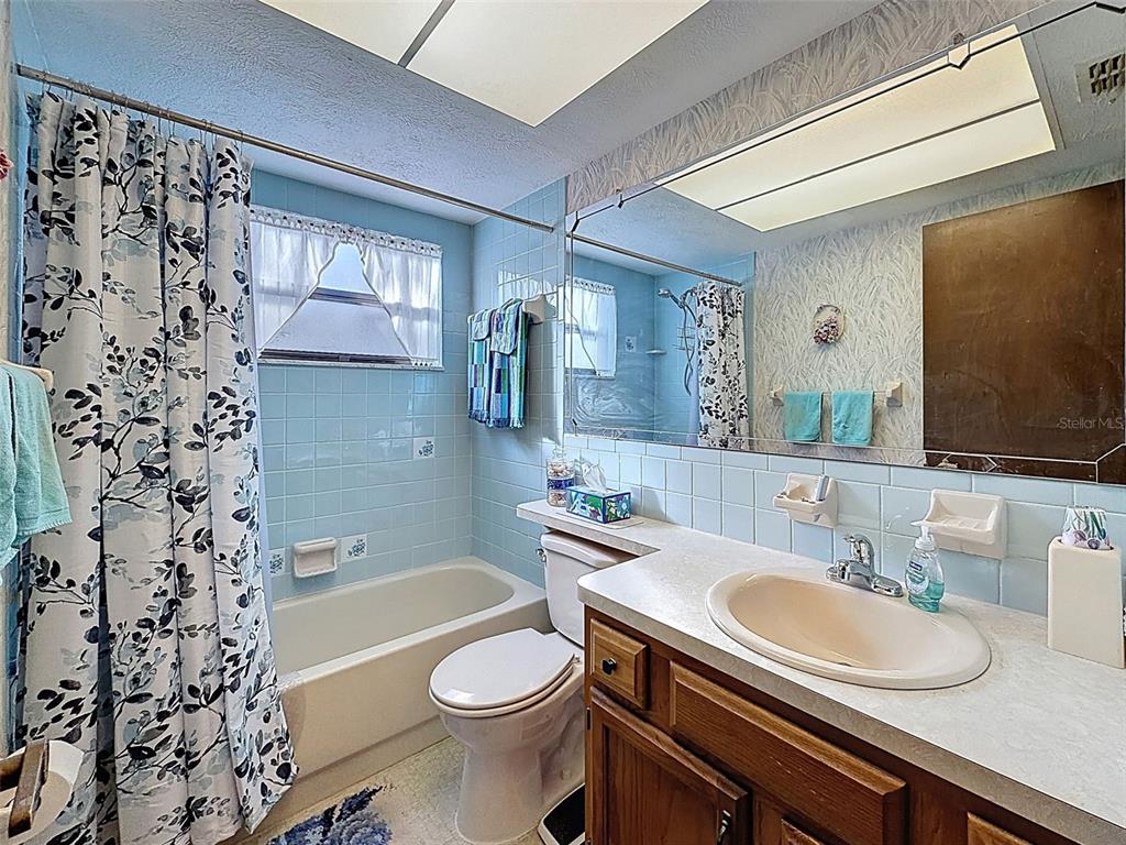 12229 Cedro Street Spring Hill, FL 34609 - Photo 29 of 50 a bathroom with a granite countertop sink toilet a mirror a bathtub and shower
