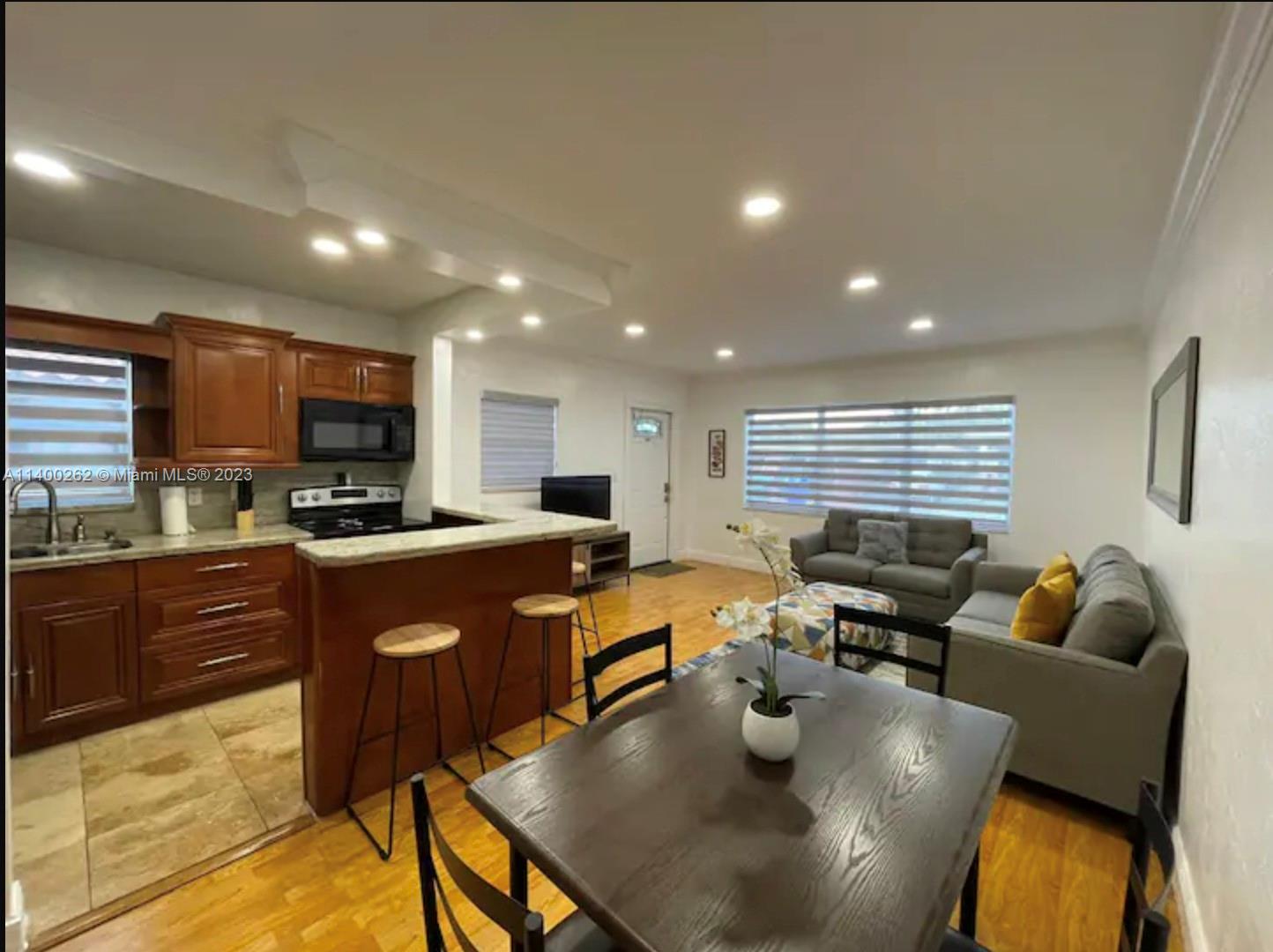 1232 Southwest 30th Place Miami, FL 33135 - Photo 5 of 7 a kitchen with stainless steel appliances granite countertop a refrigerator a sink dishwasher a dining table and chairs with wooden floor