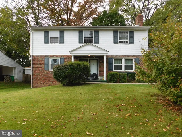 a front view of house with yard and trees in the background