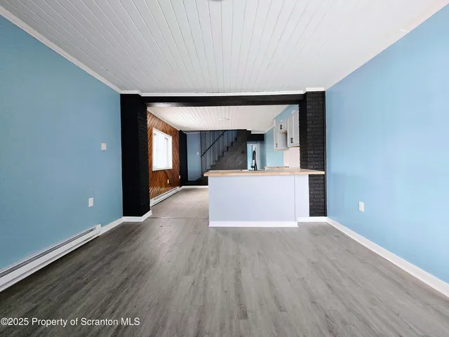 a view of a big room with wooden floor and a kitchen