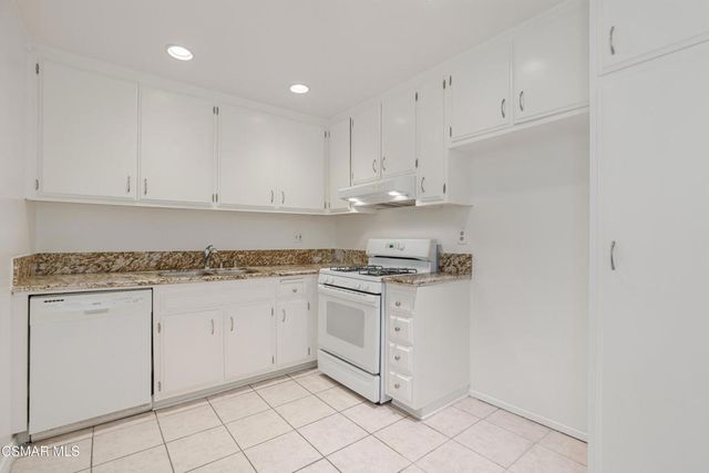a kitchen with granite countertop white cabinets and white appliances