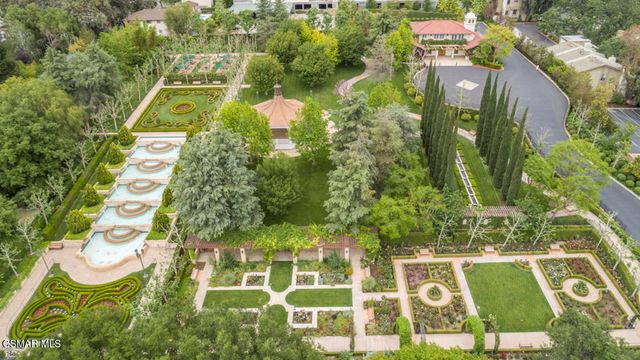 a view of a fountain with big fountain plants and large trees