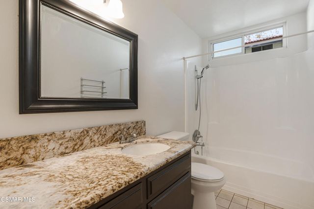 a bathroom with a granite countertop sink a toilet and a mirror