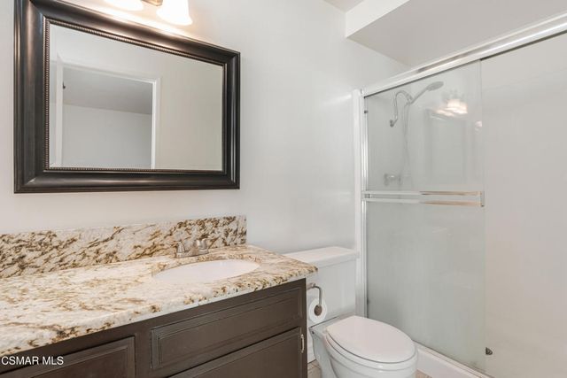 a bathroom with a granite countertop sink a toilet and mirror