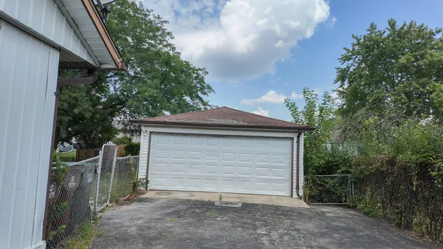 a backyard of a house with plants and large tree
