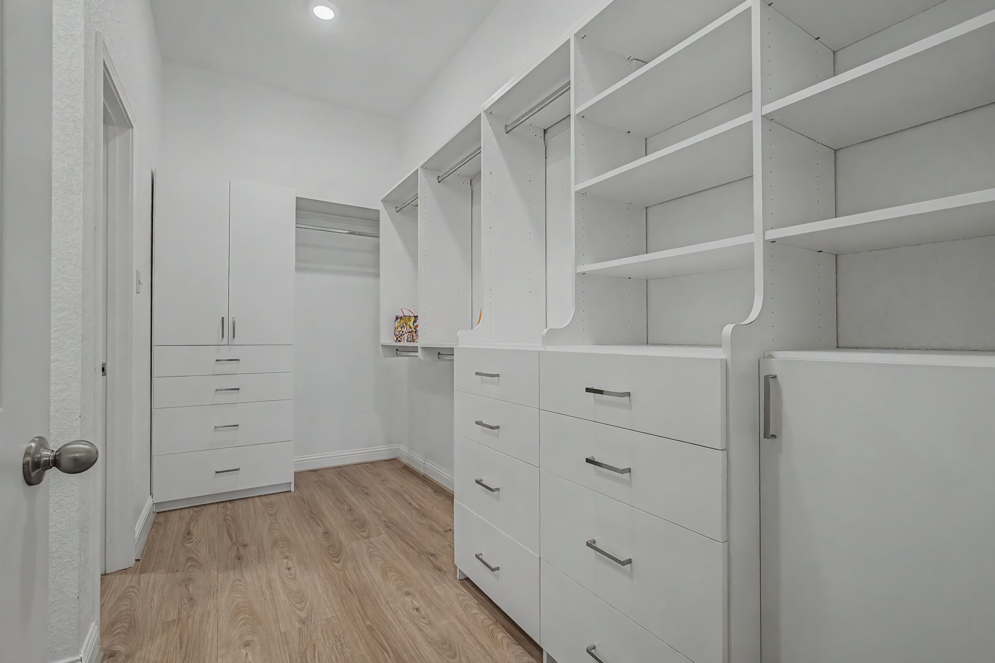 21339 Sierra Point Lane Porter, TX 77365 - Photo 22 of 36 Spacious walk-in closet with ample shelving, drawers, and hanging space, featuring a sleek, modern design with white cabinetry and wood flooring.