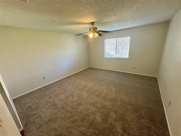 an empty room with a ceiling fan and a window