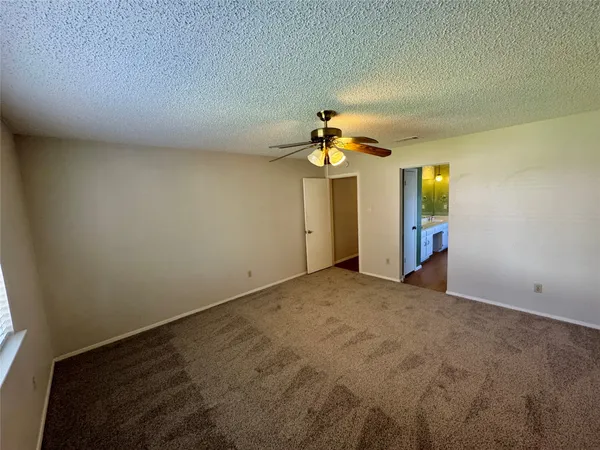 an empty room with a chandelier fan and windows