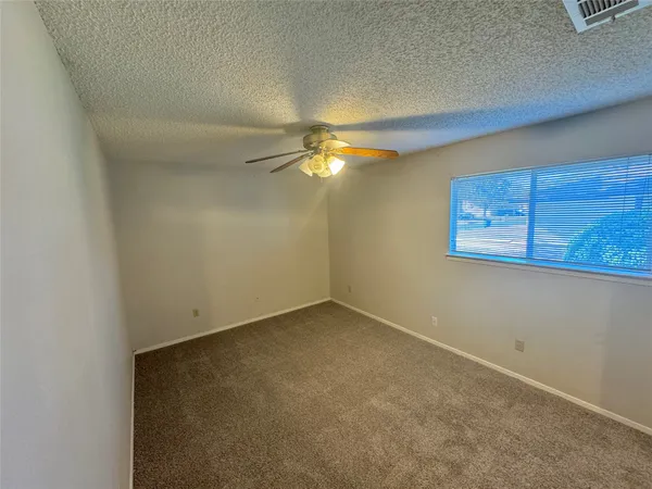 an empty room with a ceiling fan and a window
