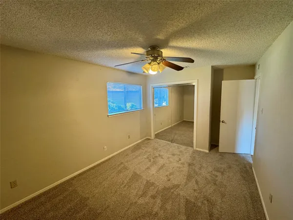an empty room with windows and fan