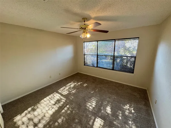 en empty room with windows and ceiling fan