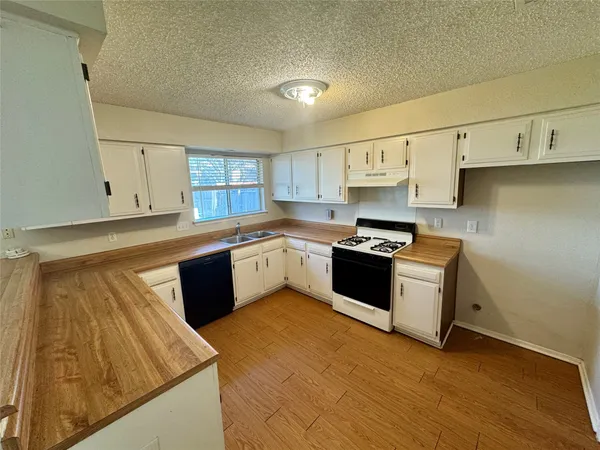 a kitchen with granite countertop a sink cabinets and stainless steel appliances