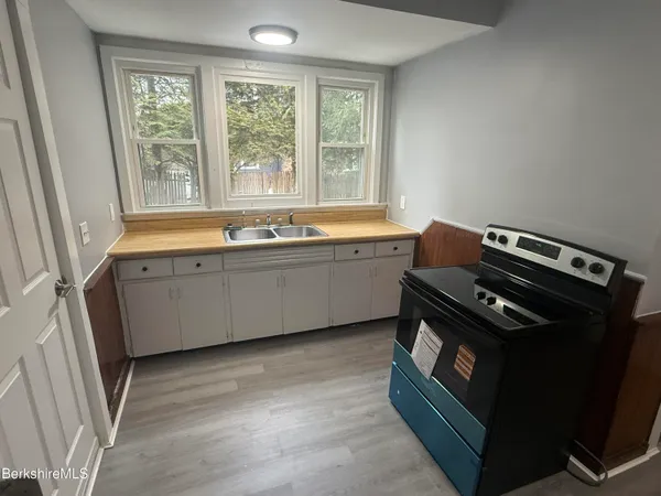 a view of a kitchen with a sink a window and wooden floor