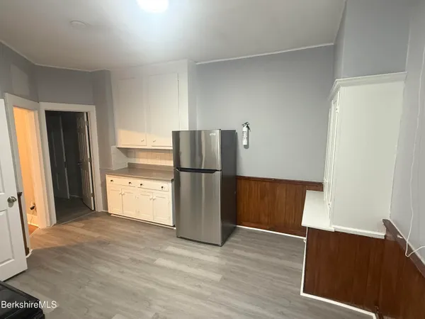 a kitchen with a refrigerator and a wooden floor