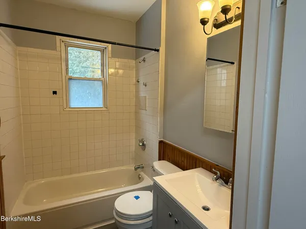 a bathroom with a bathtub shower sink vanity and toilet