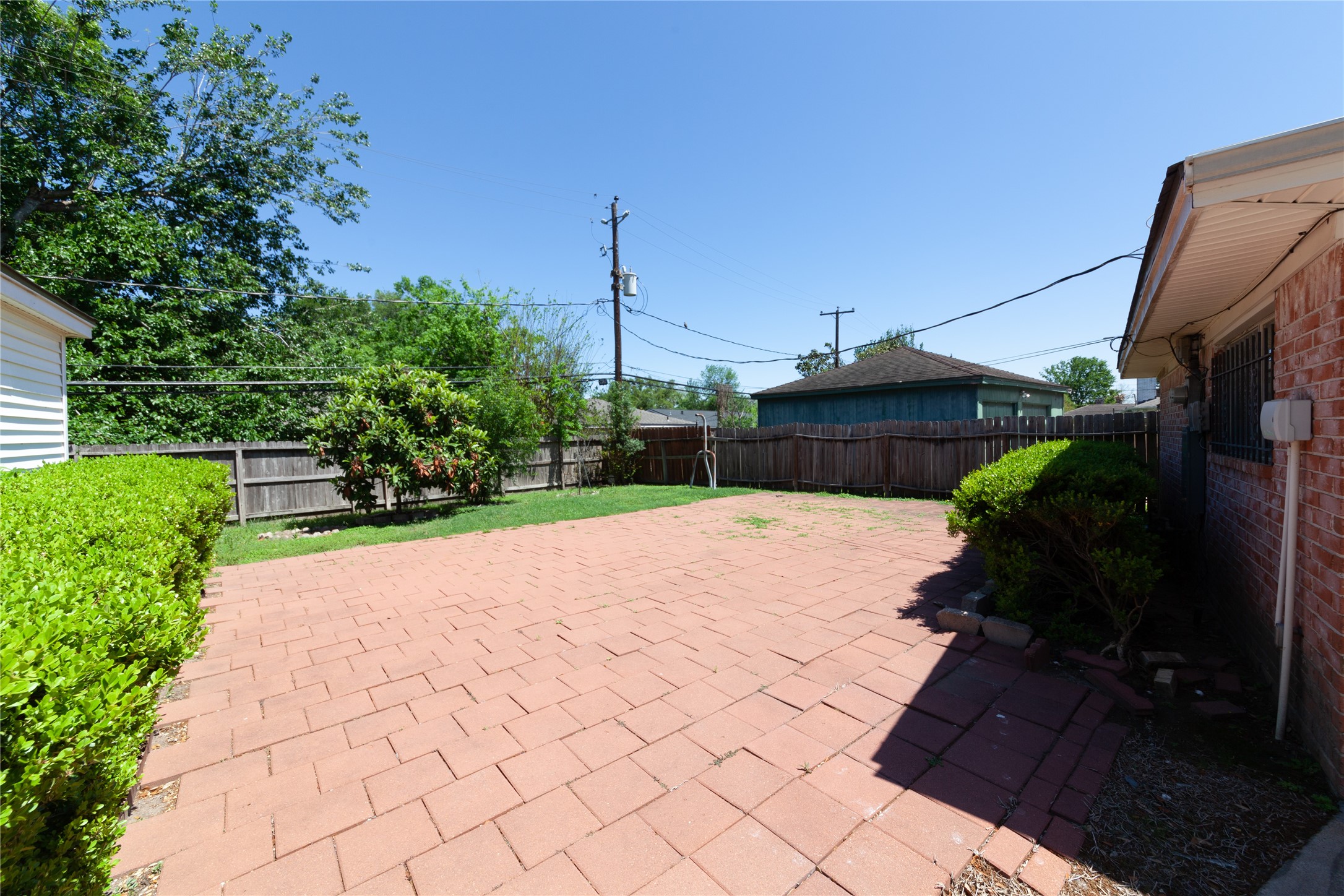8826 Roos Road Houston, TX 77036 - Photo 39 of 42 A spacious backyard with a large paved patio area, surrounded by a wooden fence and greenery, perfect for outdoor activities and relaxation.