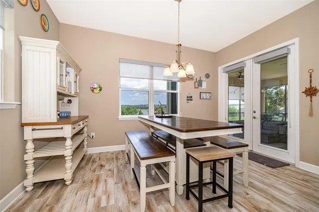 a dining room with wooden floor a chandelier a wooden table and chairs