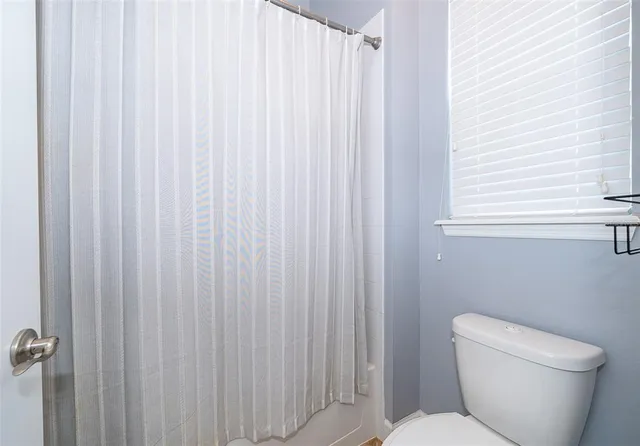 a white toilet sitting next to a shower