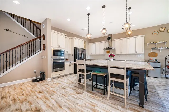 a kitchen with stainless steel appliances kitchen island granite countertop a table chairs and wooden cabinets