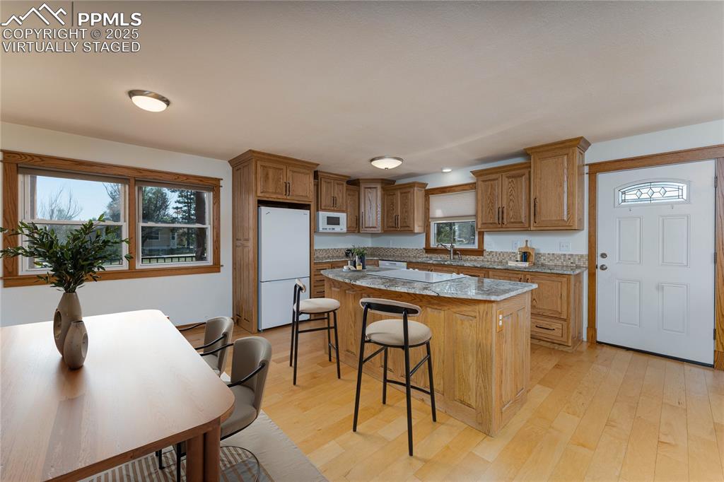 1075 8th Street Calhan, CO 80808 - Photo 5 of 45 a kitchen with stainless steel appliances granite countertop a stove a refrigerator a sink a dining table and chairs with wooden floor