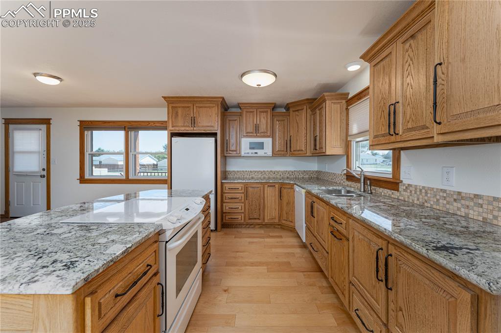 1075 8th Street Calhan, CO 80808 - Photo 7 of 45 a large kitchen with granite countertop a sink and dishwasher a stove top oven with wooden floor