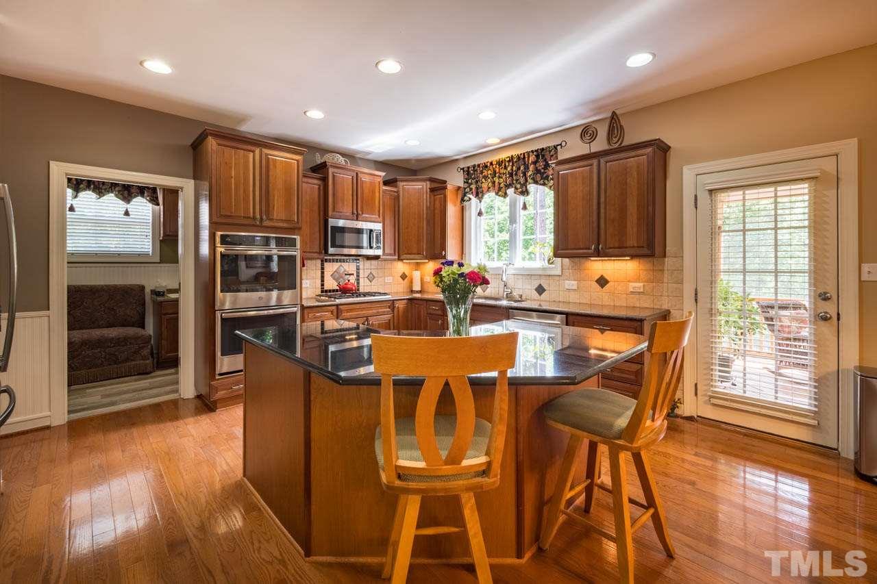 4445 Fairview Ridge Lane Apex, NC 27539 - Photo 8 of 30 Features work island with bar seating, granite tops, 42" wood cabinets, tile backsplash, double ovens,