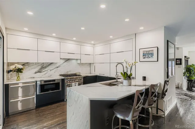 a kitchen with stainless steel appliances kitchen island granite countertop a table chairs stove and white cabinets