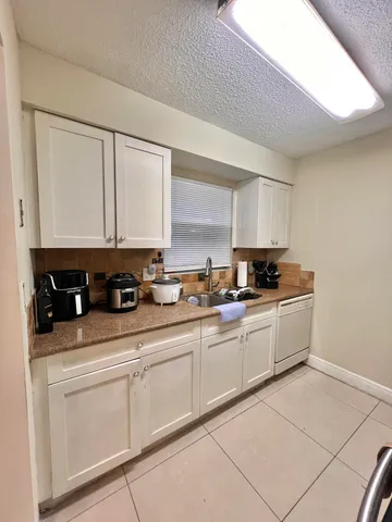 a kitchen with granite countertop white cabinets and white appliances