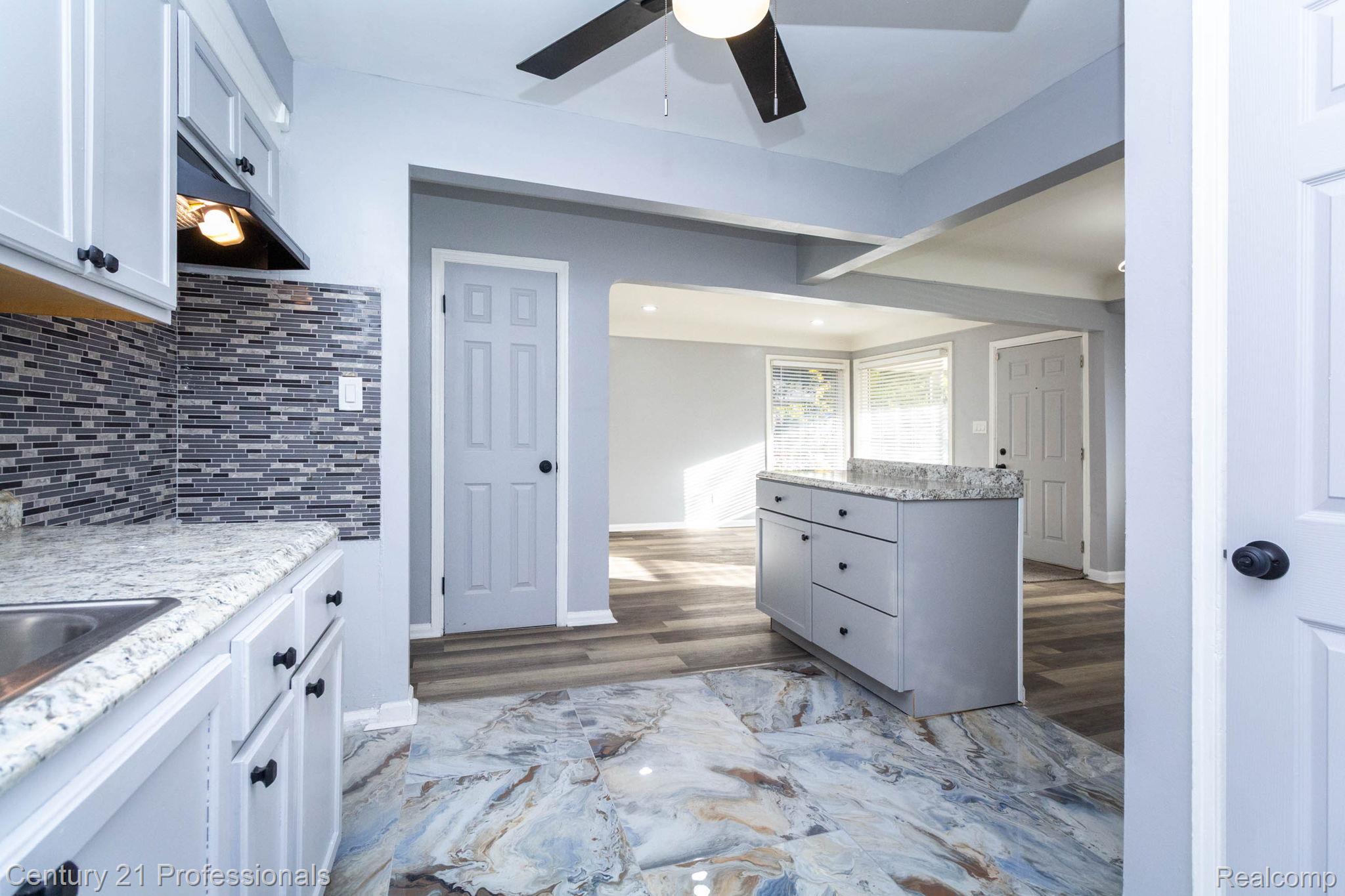 18951 Edinborough Road Detroit, MI 48219 - Photo 12 of 47 Kitchen with ceiling fan, light stone countertops, backsplash, dark wood-type flooring, and gray cabinetry