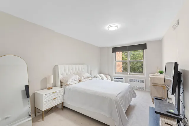 a bedroom with a bed wooden floor and a large window