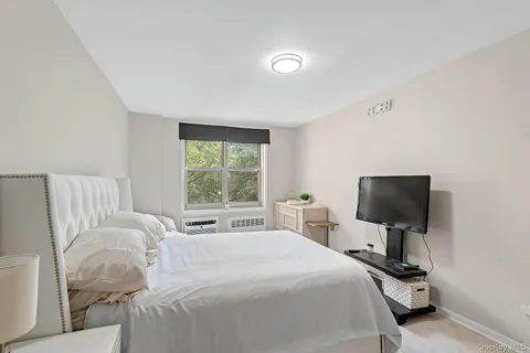 a bedroom with a bed tv and window