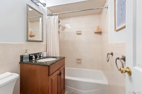 a bathroom with a granite countertop sink mirror vanity and a bathtub