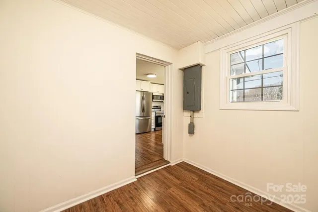a view of an empty room with wooden floor and a window
