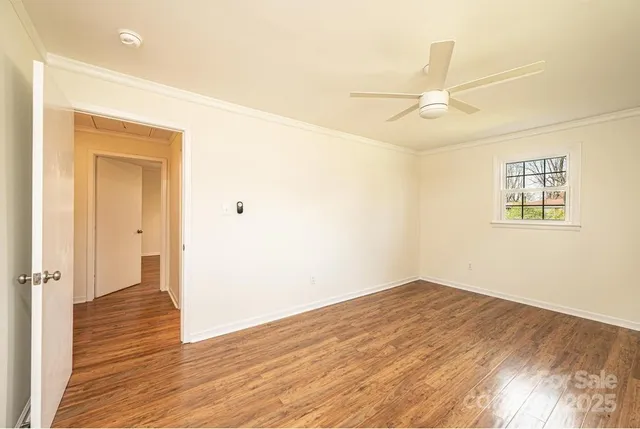 an empty room with wooden floor windows and ceiling fan