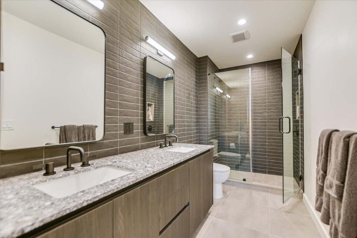 84 East Avenue, Unit 3909 Austin, TX 78701 - Photo 7 of 26 a bathroom with a granite countertop sink a mirror and a bathtub