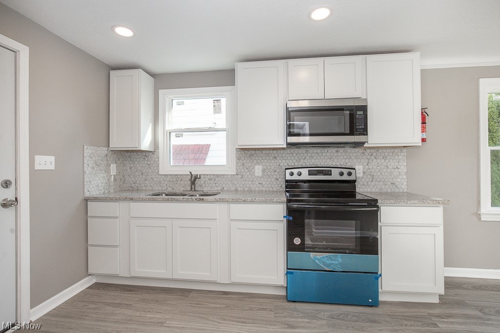 19109 Libby Road Maple Heights, OH 44137 - Photo 11 of 32 Kitchen with a wealth of natural light, range with electric stovetop, and white cabinets
