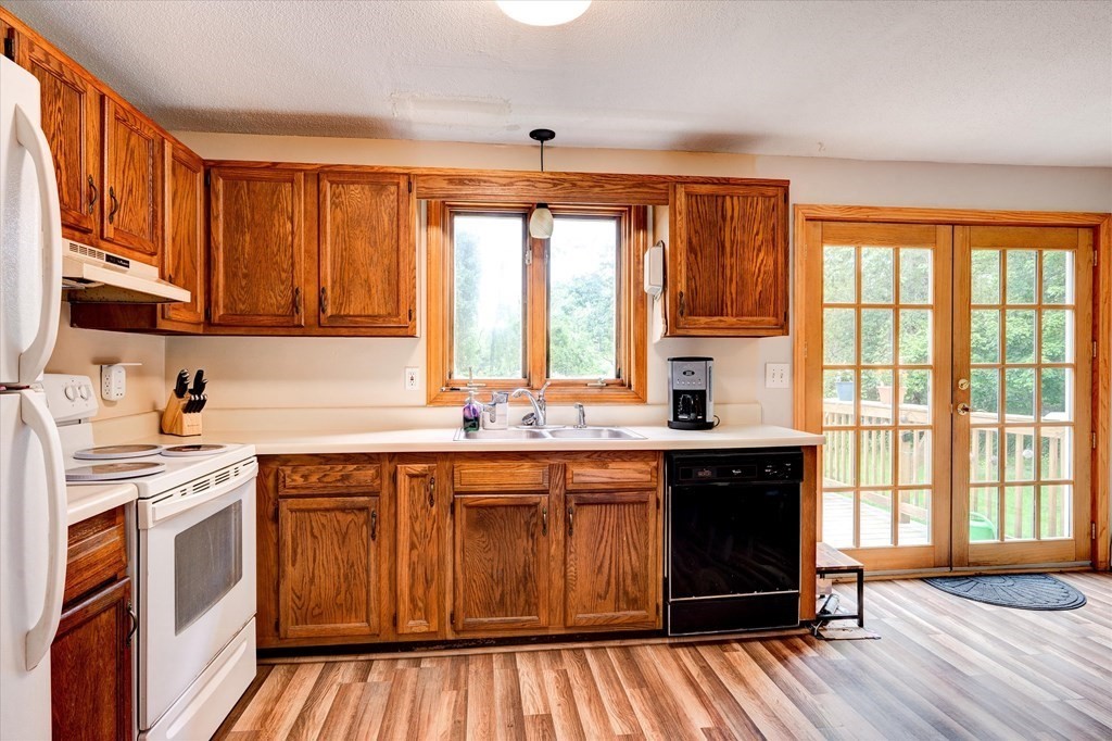 6 Litchfield Road, Unit A Londonderry, NH 03053 - Photo 5 of 28 a kitchen with a sink stove and wooden cabinets