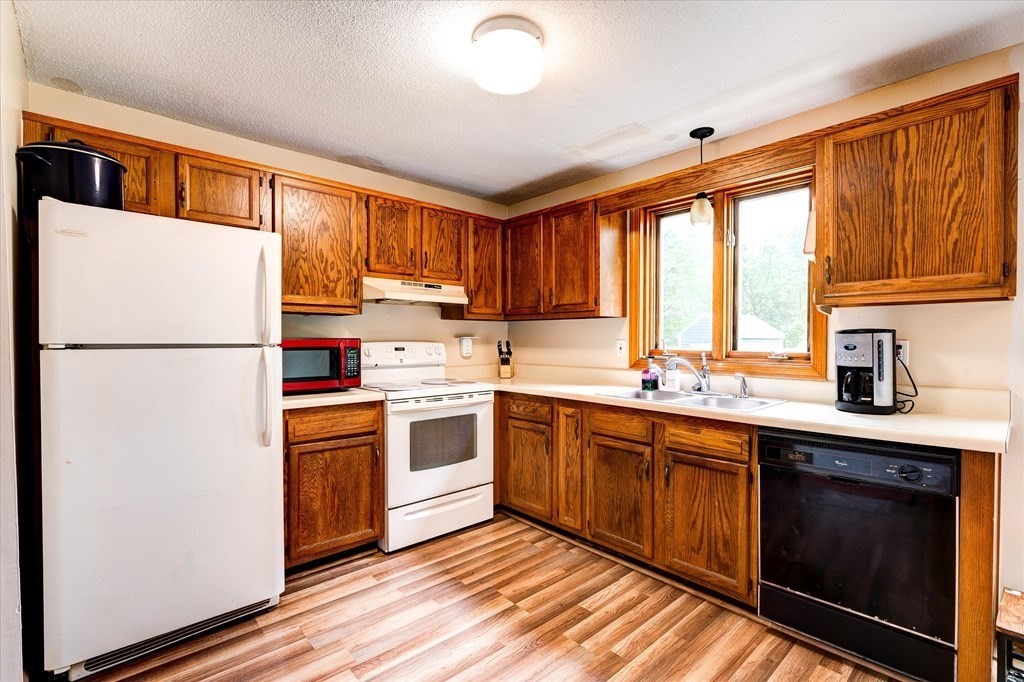6 Litchfield Road, Unit A Londonderry, NH 03053 - Photo 6 of 28 a kitchen with stainless steel appliances granite countertop a refrigerator a sink dishwasher a stove with white cabinets and wooden floor