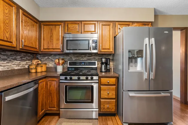 a kitchen with stainless steel appliances granite countertop a refrigerator and a stove top oven