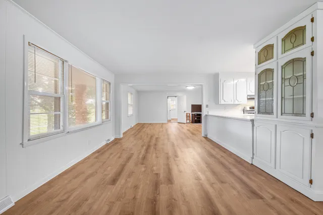 a large white kitchen with granite countertop a stove a sink and white cabinets with wooden floor