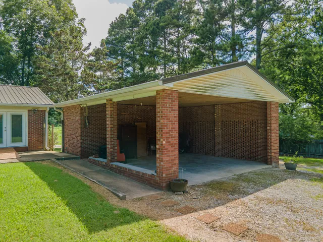 a view of a house with a yard plants and large tree