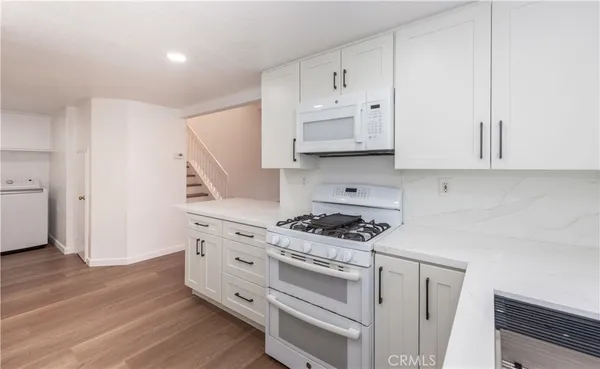 a kitchen with cabinets appliances and a wooden floor