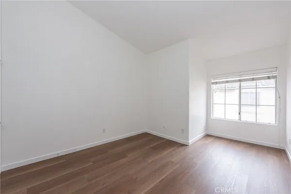 an empty room with wooden floor and window