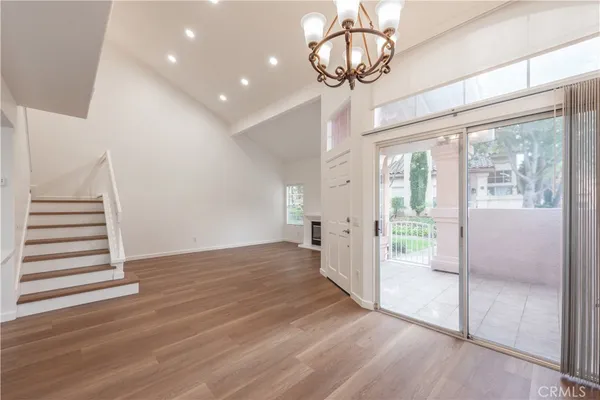 a view of a hallway with wooden floor and chandelier