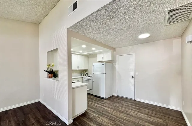 a view of a kitchen with a refrigerator white cabinets and wooden floor