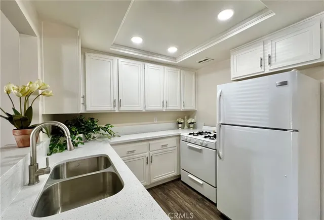 a white kitchen with sink a refrigerator and a sink
