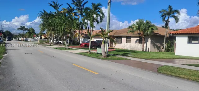a view of a house with a yard and palm trees