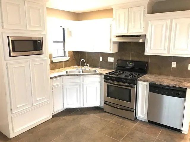 a kitchen with granite countertop white cabinets and appliances